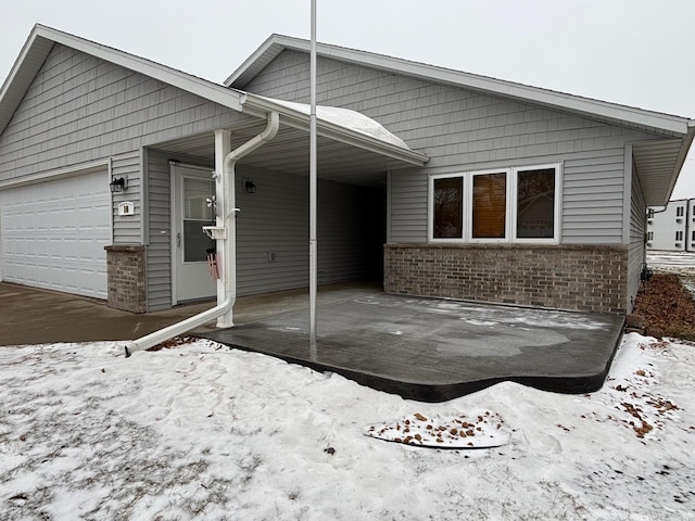 snow covered rear of property featuring a garage