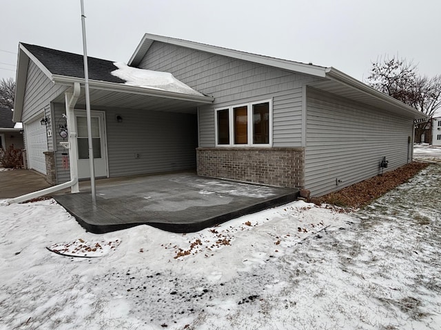 snow covered back of property with a garage