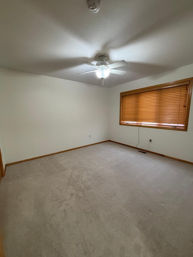 spare room with a textured ceiling, light colored carpet, and ceiling fan