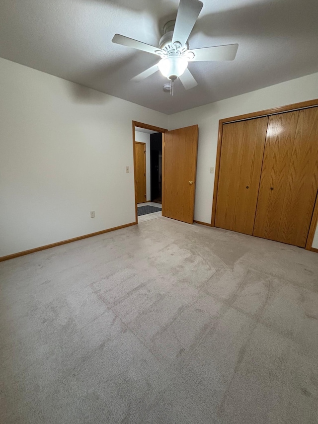 unfurnished bedroom featuring ceiling fan, a closet, and light carpet