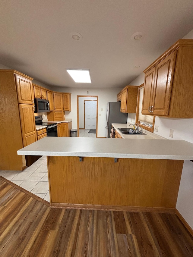 kitchen featuring kitchen peninsula, appliances with stainless steel finishes, light wood-type flooring, and sink