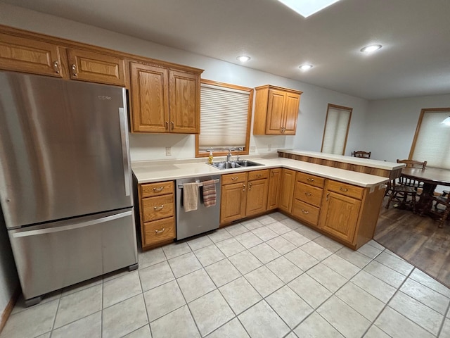 kitchen with light wood-type flooring, kitchen peninsula, sink, and appliances with stainless steel finishes