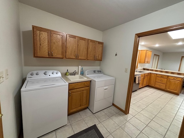 laundry room featuring cabinets, light tile patterned floors, washing machine and dryer, and sink