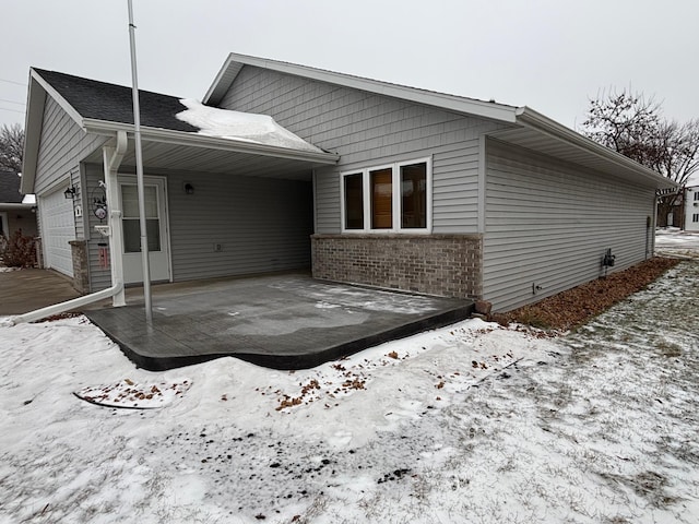 10 Townhouse Rd, Morris, MN 56267 - snow covered house featuring brick siding, a garage, and a patio area