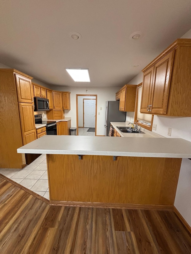 10 Townhouse Rd, Morris, MN 56267 - kitchen with stainless steel appliances, a peninsula, light wood-type flooring, light countertops, and a kitchen breakfast bar