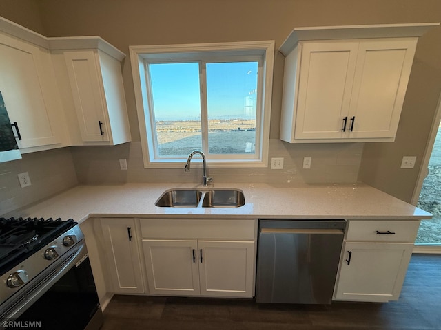 kitchen with tasteful backsplash, sink, white cabinets, and appliances with stainless steel finishes