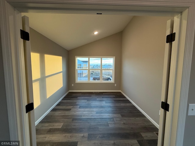 spare room with lofted ceiling and dark wood-type flooring