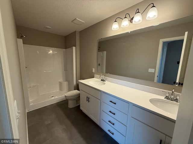 bathroom with vanity, a textured ceiling, toilet, and walk in shower