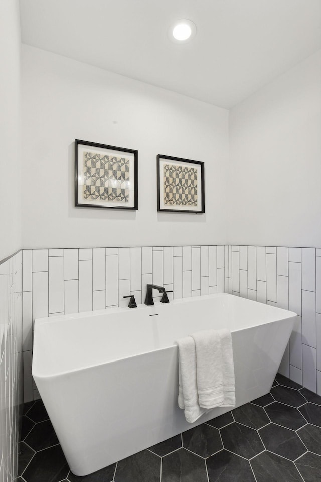 bathroom with tile patterned flooring, a washtub, and tile walls