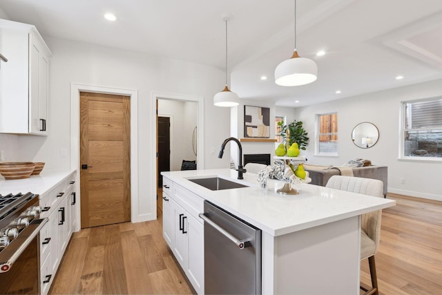 kitchen with sink, stainless steel appliances, a center island with sink, white cabinets, and light wood-type flooring