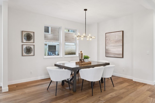 dining area with light hardwood / wood-style floors and an inviting chandelier