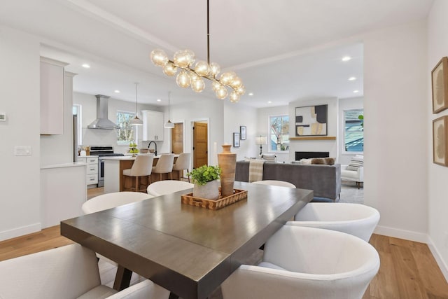 dining area with an inviting chandelier, sink, and light hardwood / wood-style flooring