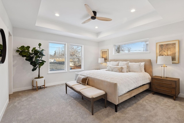 bedroom featuring ceiling fan, light carpet, and a tray ceiling