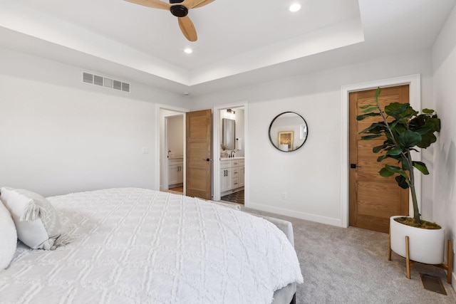 carpeted bedroom with ensuite bathroom, ceiling fan, a tray ceiling, and sink