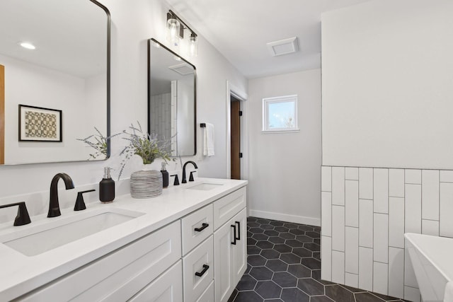 bathroom with tile patterned floors, a tub to relax in, and vanity