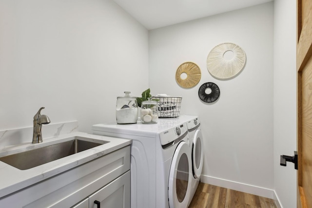 washroom featuring washer and clothes dryer, light hardwood / wood-style floors, cabinets, and sink