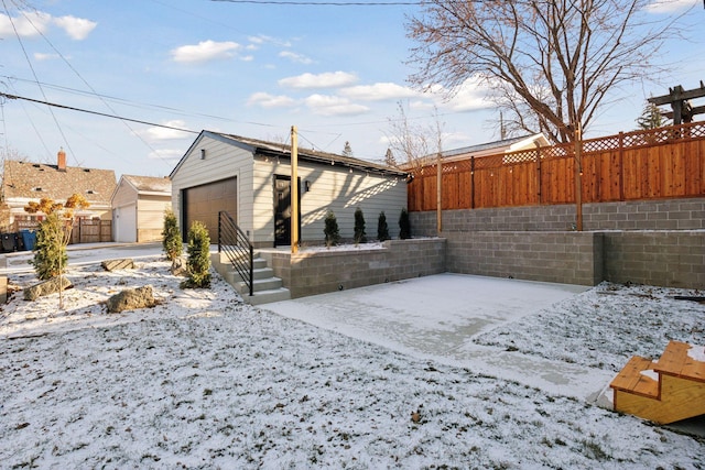 snowy yard featuring an outbuilding and a garage