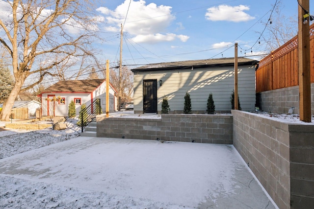 snow covered house featuring a storage shed