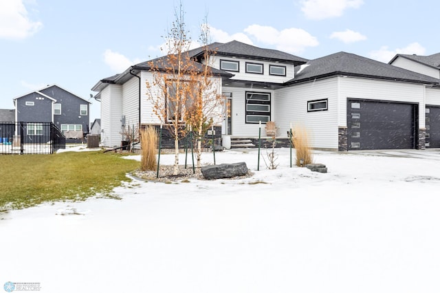 snow covered back of property featuring a yard and a garage