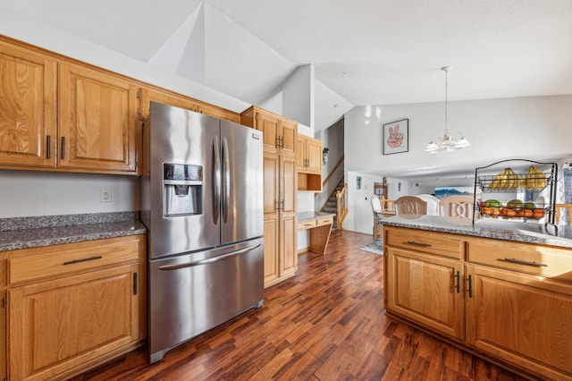 kitchen with lofted ceiling, dark hardwood / wood-style floors, stainless steel fridge with ice dispenser, decorative light fixtures, and dark stone counters