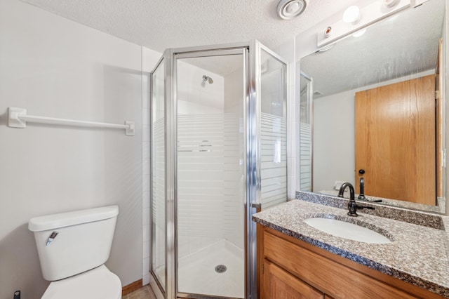 bathroom with vanity, a shower with shower door, a textured ceiling, and toilet