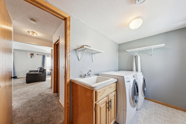 clothes washing area with sink, cabinets, light colored carpet, washing machine and clothes dryer, and a textured ceiling