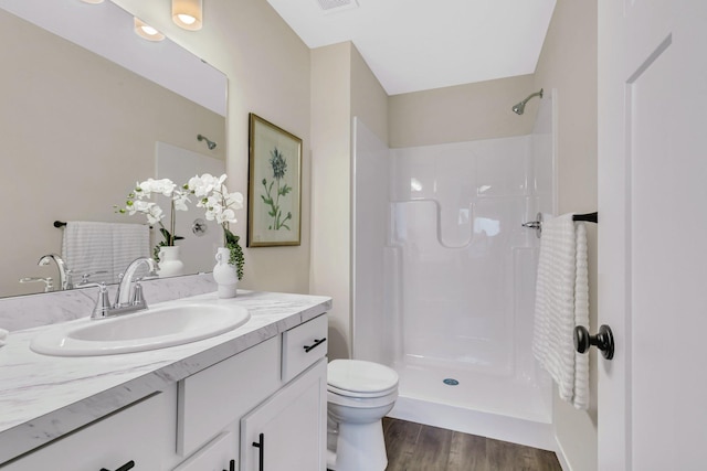 bathroom featuring a shower, wood-type flooring, vanity, and toilet