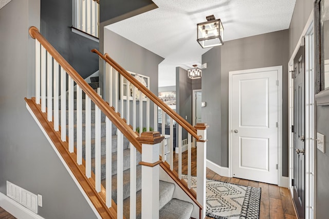 foyer entrance featuring a textured ceiling and dark wood-type flooring