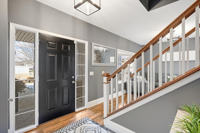 foyer entrance with light hardwood / wood-style floors and a textured ceiling