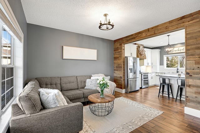 living room featuring hardwood / wood-style floors, a textured ceiling, an inviting chandelier, and wood walls