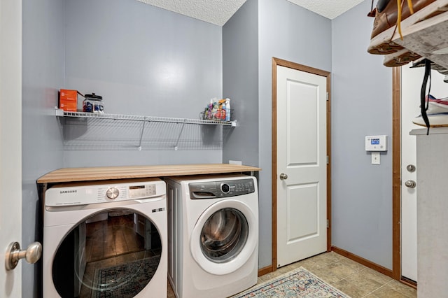 clothes washing area featuring light tile patterned floors, a textured ceiling, and washer and clothes dryer