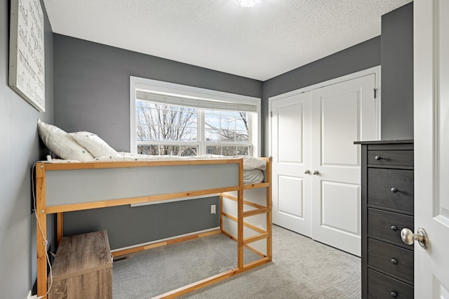 bedroom featuring light colored carpet, a textured ceiling, and a closet