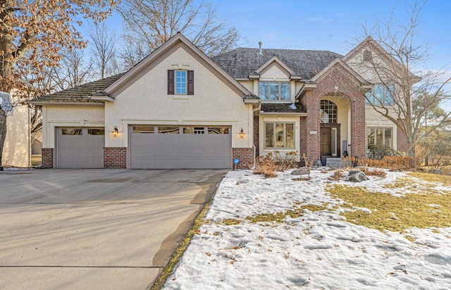 view of front of home featuring driveway, stucco siding, and brick siding