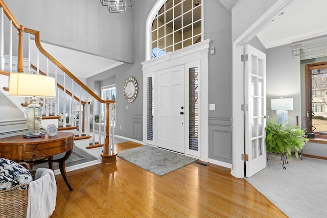 entryway with crown molding, visible vents, stairway, wood finished floors, and baseboards