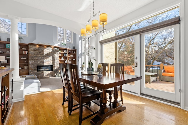 dining room with a towering ceiling, a fireplace, and wood finished floors