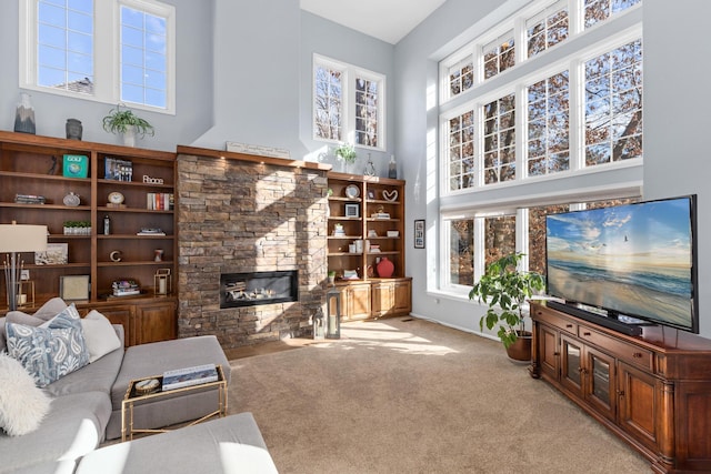 living room featuring a towering ceiling, a fireplace, and light colored carpet