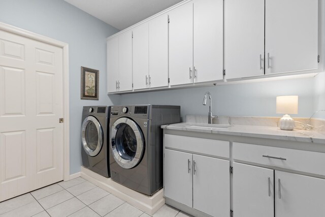 clothes washing area featuring cabinet space, washing machine and dryer, a sink, and light tile patterned flooring