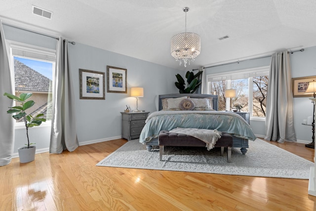 bedroom featuring lofted ceiling, baseboards, visible vents, and light wood finished floors