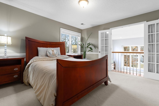 bedroom with french doors, visible vents, light carpet, and a textured ceiling