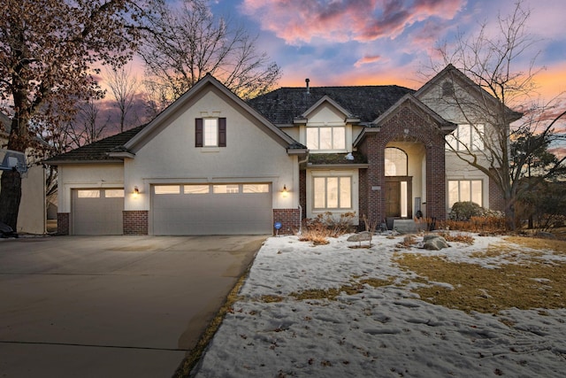 view of front of property with driveway, stucco siding, an attached garage, and brick siding