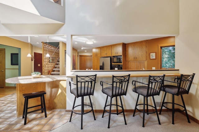 kitchen with black appliances, kitchen peninsula, and a breakfast bar area