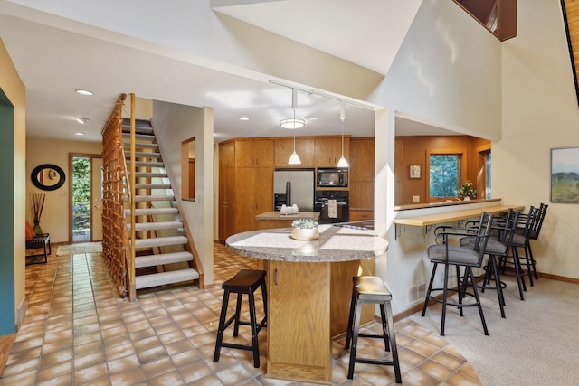 kitchen featuring hanging light fixtures, kitchen peninsula, a breakfast bar, and black appliances