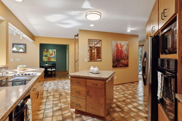 kitchen with appliances with stainless steel finishes, a kitchen island, and light tile patterned flooring