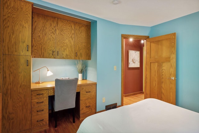 bedroom with wood-type flooring and built in desk