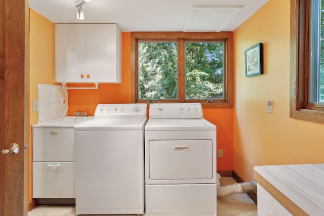 clothes washing area with cabinets, washing machine and dryer, and a wealth of natural light