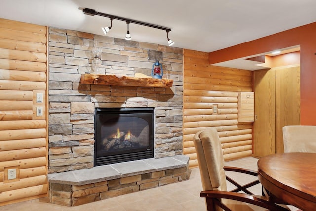 interior space with a fireplace, log walls, and track lighting