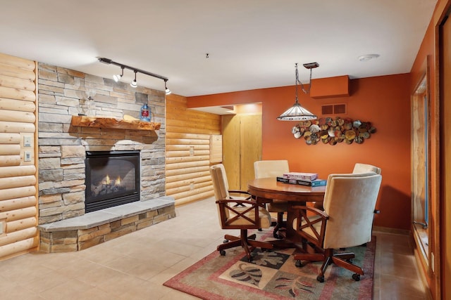 dining space with tile patterned floors, rustic walls, a fireplace, and track lighting