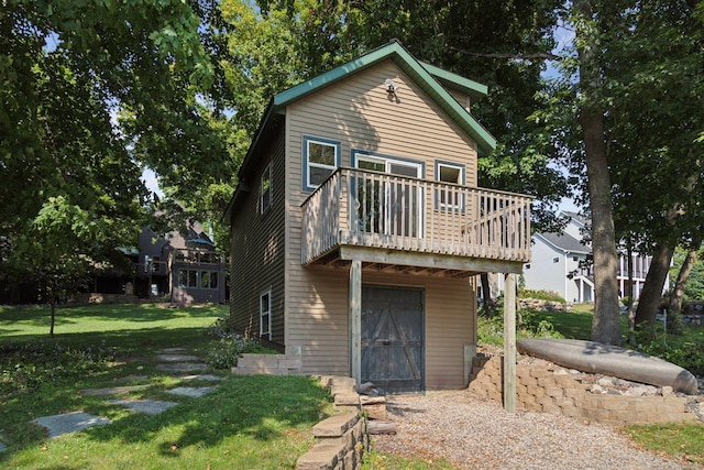 rear view of property featuring a yard and a balcony