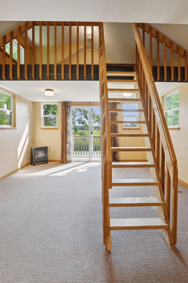 staircase featuring a wood stove, carpet, and a healthy amount of sunlight