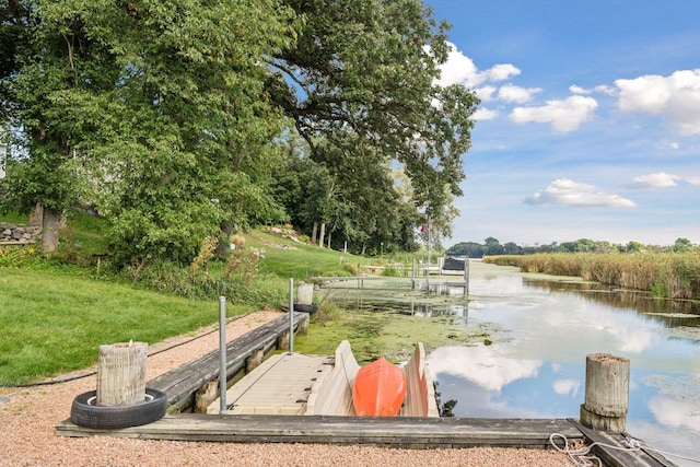 exterior space with a lawn, a water view, and a boat dock